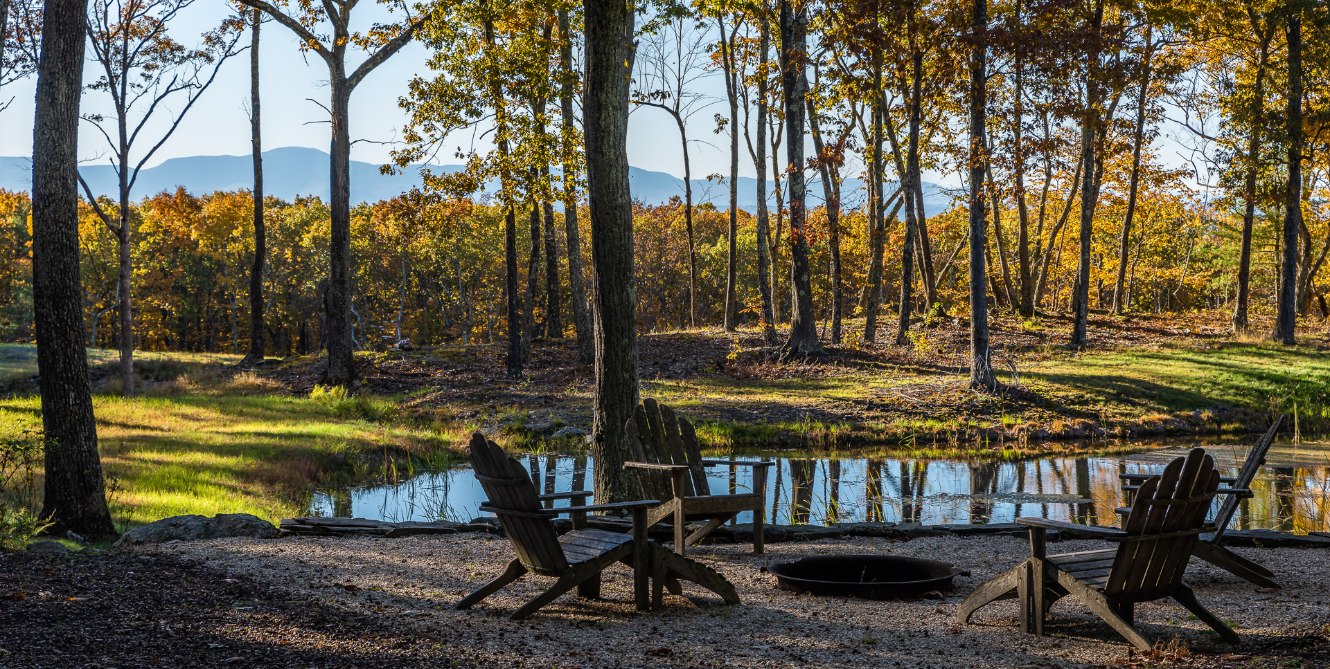 Adirondack chairs grouped around a pond with mountain views in the background