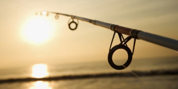 A fishing pole silhouetted against a sunset on the water